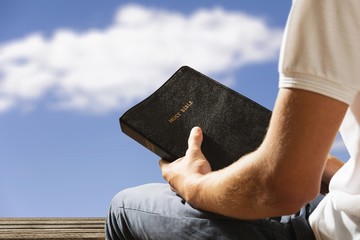 Man holding old bible book on green