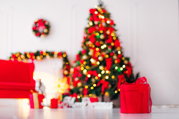 red box with a ribbon on the background of a room with a blurred Christmas tree, a sofa and a...
