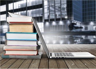 Stack of books with laptop on table