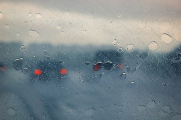 Blurry car silhouette seen through water drops on the car windshield