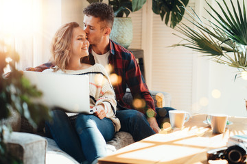 Couple in love. Young family watching TV series using laptop and sitting on the sofa