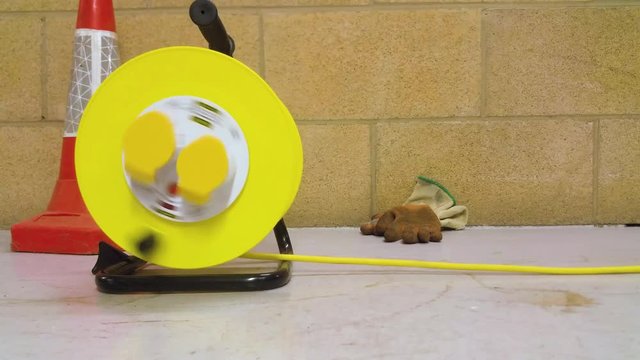 Yellow extension lead drum being reeled out along a plant room floor