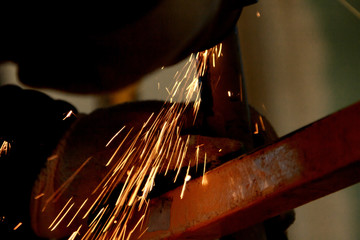 worker grinding cutting metal sheet with grinder machine and sparks