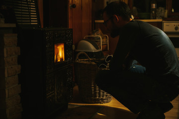 man sitting in front of an oven while watching the flames