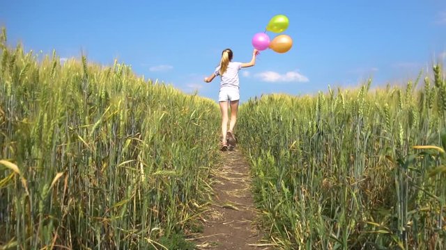 Female with balloons rinning in field