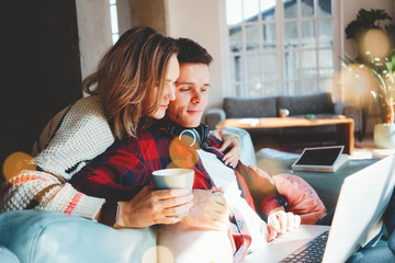 Pretty couple in love at home. Man and woman sitting on the couch and watching TV series on laptop...