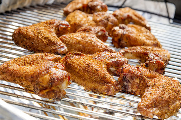 Chicken wings are cooking on the barbecue grill