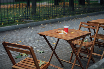 Coffee to go and a croissant on a table of a street cafe in the autumn