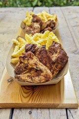 Portion of grilled chicken wings and chips in trays