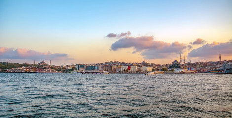 Fototapeta na wymiar Touristic landmarks from sea voyage on Bosphorus. Cityscape of Istanbul at sunset - old mosque and turkish steamboats, view on Golden Horn.