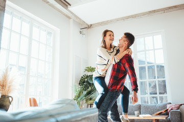Lovely couple at home. Spending happy time together and dancing in the big spacious room, laughting and hugging. Bright loft apartment