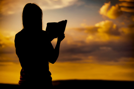 Girl Reading The Bible At Sunset Silhouette