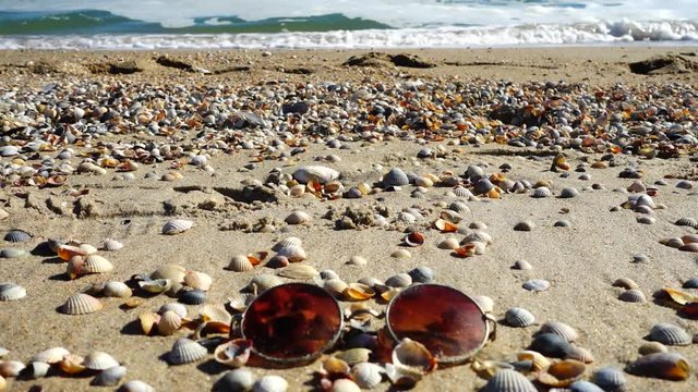 	Sunglasses on the sandy beach. Slow motion.