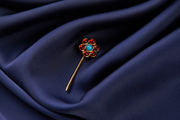 Gold hairpin with ruby precious stone on blue silk background with copy spce. Beautiful precious...