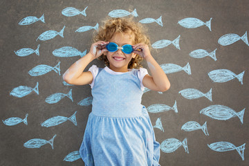 Portrait of a young beautiful girl lying on the street, surrounded by chalk drawings of blue fish 