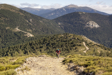 Women and mountain biking man riding on bikes in the mountains forest landscape. MTB track cycling couple enduro flow trail. Outdoor sports activity. Hard and steep climb