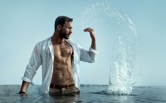 handsome brutal man in wet white short splashes water around him on a beach or swimming pool feeling healthy , fit and free