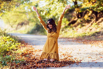 Young pretty woman playing with leaves in a park at autumn day