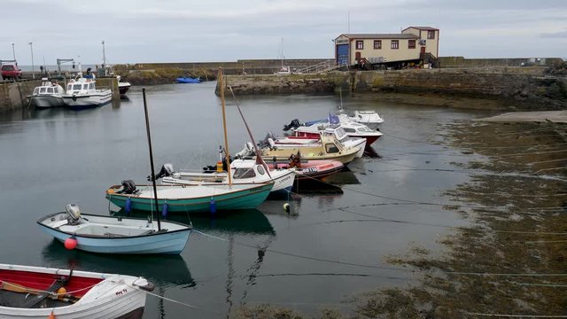 Small motorboats moored at low tide in harbor-St Abbs a small fishing village on the southeastern coast of Scotland, within the Coldingham parish of Berwickshire.