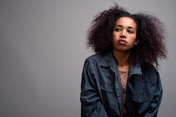 Young beautiful African woman against gray background