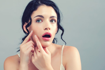 Young woman with skin blemish theme on a gray background