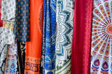 Indian fabrics hanging on the counter. Trade in fabrics from india. Fabric with patterns and patterns.