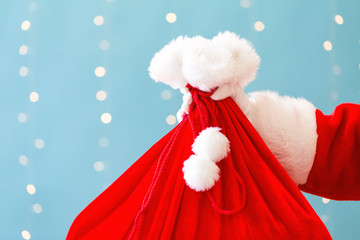 Santa holding a red sack on a shiny light blue background