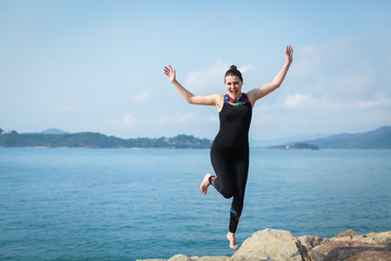 Portrait of young caucasian woman jumping with joy and euphoria at the beach