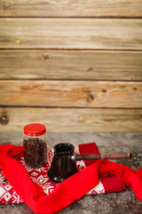 Close up of glass jar with Coffee beans and black ceramic turk on wooden background with red knitwear