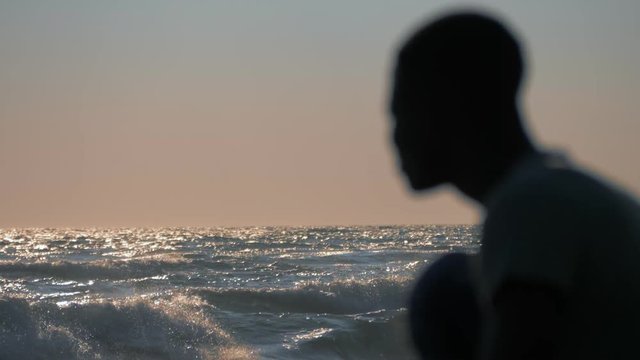 Migration, refugee, home. Migrant silhouette at sunset observing the ocean