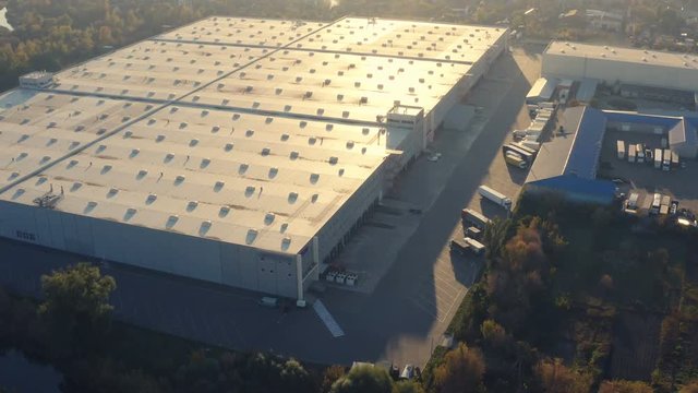 Aerial view of a big logistic warehouse terminal with a semi-trailer trucks on the parking