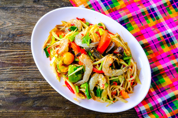 Som Tam Seafood (Spicy Papaya Salad) with salted crab, on wooden table ( Thai food)