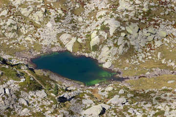 Autumn hiking in Aosta valley, Gressoney, Italy. View of alpine lake of Goudin from Point Sella near the Coda mountain refuge.