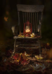 Garden scene with fall leaves, rustic oil lamp on vintage wooden chair