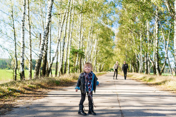Little cute girl posing on the road in the birch forest in autumn time