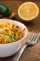 Rice noodles with cucumber, carrot, pepper, lemon on wooden background.
