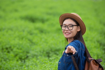 Woman traveler with backpack  hat and looking at lies on a meadow in the mountains.