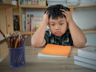 Cute asian children is bored and tired with doing homework on desk in the room. education concept.