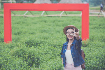 Woman traveler with backpack  hat and looking at lies on a meadow in the mountains.