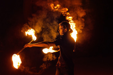 Fire show. Fire dancer dances with two Staff. Night performance. Dramatic portrait. Fire and smoke....