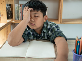 Cute asian children is bored and tired with doing homework on desk in the room. education concept.