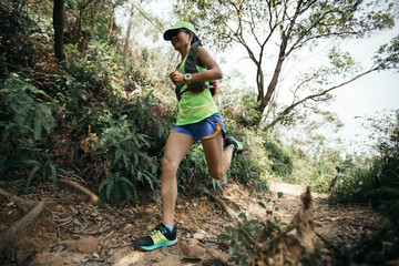Young woman trail runner running on tropical forest trail