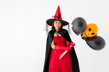 Studio shot Asian woman in red costume witch  hand holding a orange and black balloon isolated on white background, concept for halloween fashion festival