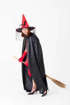 Woman in red dress costume for famale witch holding broomstick on white background with copy space. Concept for funny activity in halloween festival