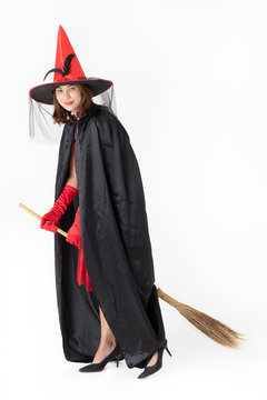 Woman witch in red witch costume riding broomstick, studio shot on white background. Concept for funny dressing in halloween festival