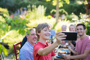 during a bbq a young boy does a selfie with the whole family