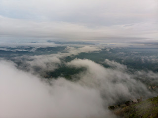 Aerial view of nature scenery. An aerial shot of hill with cloudy and misty background.