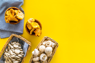 Collect mushroom concept. Champignons, oysters, chanterelles in basket on yellow background top...
