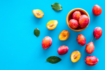Summer harvest of red plum.  Red plum and leaves pattern on blue background top view space for text