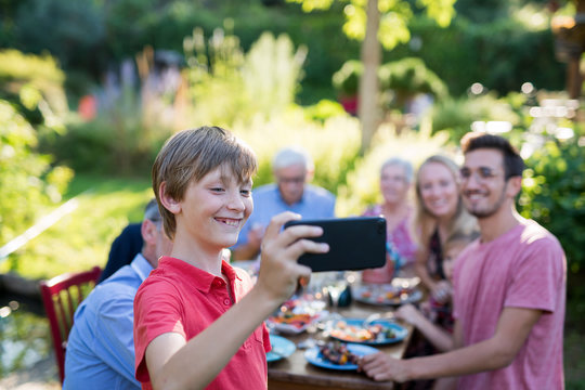 during a bbq a young boy does a selfie with the whole family